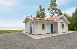 una pequeña casa blanca con puertas azules en una entrada en Awesome Home In Mellerud With Lake View, en Mellerud