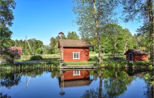 a small red house sitting on top of a lake at Awesome Apartment In Rnneshytta With Kitchen in Rönneshytta