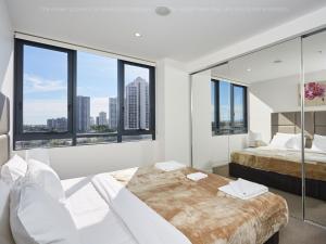 a white bedroom with a large bed and large windows at Ruby Gold Coast By Serain in Gold Coast