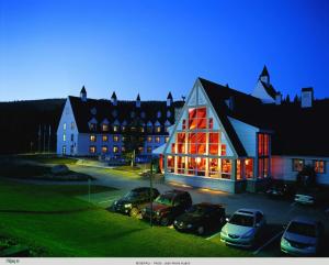 a large building with cars parked in front of it at Gîte du Mont-Albert - Sepaq in Sainte-Anne-des-Monts