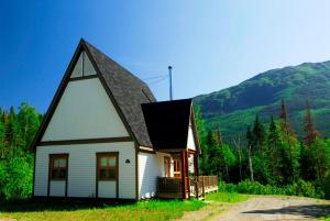 una pequeña casa blanca con techo negro en Gîte du Mont-Albert - Sepaq, en Sainte-Anne-des-Monts