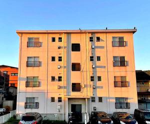 ein hohes Gebäude mit davor geparkt in der Unterkunft Hayakawa&2rooms&48m2&5-6pplmax&Best location&well designed 早川駅徒歩2分 釣り場まで徒歩1分 グループ滞在可能なワーケーション最適プレイス in Odawara