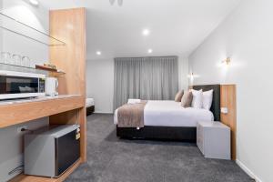 um quarto de hotel com uma cama e uma televisão em Kolmar Inn em Auckland