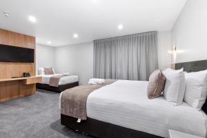 a hotel room with two beds and a television at Kolmar Inn in Auckland