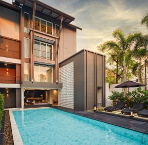 a house with a swimming pool in front of a building at KIRI HOTEL Chiang Mai in Chiang Mai