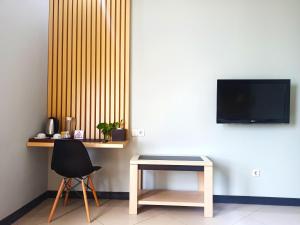 a table and a chair and a tv on a wall at Rio City Hotel in Palembang