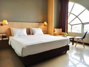 a bedroom with a large bed and a large window at Rio City Hotel in Palembang