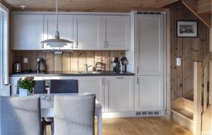 a kitchen with white cabinets and a table with chairs at Amazing Home In Mesnali With Wifi in Mesnali