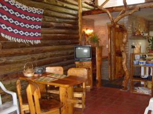 una sala da pranzo con tavolo e TV in una cabina di Cabañas El Milagro a San Roque