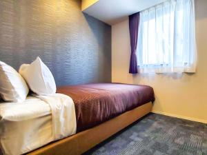 a small bedroom with a bed with a window at HOTEL LiVEMAX Tachikawa Ekimae in Tachikawa