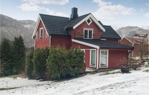une maison rouge avec un toit noir dans la neige dans l'établissement Beautiful Home In Valsyfjord With Wifi And 3 Bedrooms, à Valsøyfjord