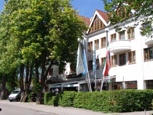 un bâtiment avec deux drapeaux devant lui dans l'établissement Hotel Kastanienhof, à Erding