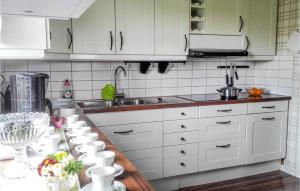 una cocina con armarios blancos y tazas en una encimera en Lovely Home In Trans With Wifi en Tranås