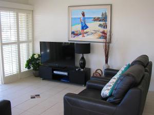 a living room with a couch and a flat screen tv at Toowoon Beach View 3br Villa 4 just steps to beach in The Entrance