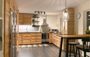 La cuisine est équipée d'armoires en bois et d'un réfrigérateur en acier inoxydable. dans l'établissement Cozy Home In Osby With Wifi, à Osby