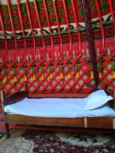 a bedroom with a bed with a red head board at Turan Handmade Yurt with Heated Floors in Karakol