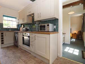 a kitchen with white cabinets and a microwave at Mortons Cottage in Castlemorton