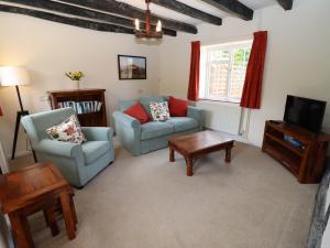 a living room with two chairs and a tv at Mortons Cottage in Castlemorton