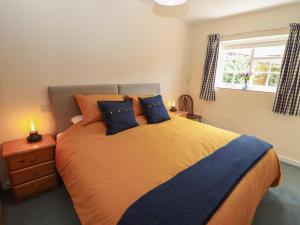 a bedroom with a bed with blue pillows and a window at Mortons Cottage in Castlemorton