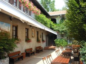 dziedziniec z drewnianymi ławkami, stołami i kwiatami w obiekcie Agriturismo Cassinazza w mieście Orsenigo