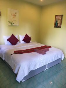 a bedroom with a large white bed with red pillows at Airee Mini House in Bang Tao Beach