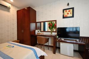ホーチミン・シティにあるLaguna Hotelのベッド、デスク、テレビが備わるホテルルームです。