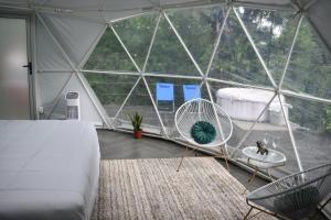 een slaapkamer met een tent met een bed en een stoel bij Roble Coral Glamping in Sarapiquí