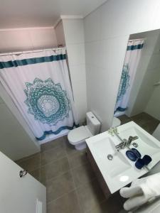 a bathroom with a sink and a toilet and a shower curtain at Apart Hotel Bauerle & Apartamentos in Temuco