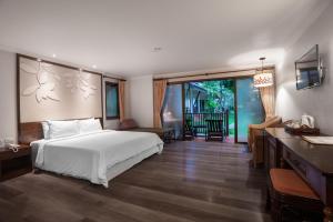 a bedroom with a bed and a desk and a television at The Leaf on The Sands by Katathani - SHA Extra Plus in Khao Lak