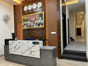 a lobby with a reception desk and clocks on the wall at Hotel Lemonade in Amritsar