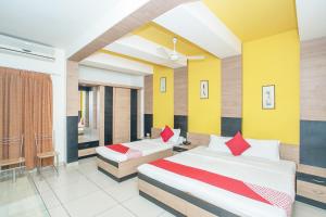 two beds in a room with yellow and red at Hotel O ABHIMAANI COMFORTS in Bengaluru
