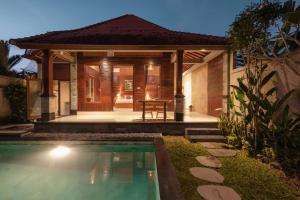 a house with a swimming pool in front of a house at Uma Galih Ubud Villa in Ubud