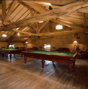 two pool tables in a room with wooden ceilings at Hôtel Les Orangeries in Lussac-les-Châteaux