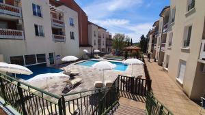 basen z parasolami obok niektórych budynków w obiekcie Le Blanc-Martel - Piscine, Climatisation & Parking w mieście Gréoux-les-Bains