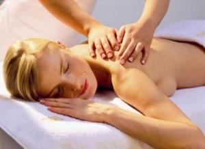 a woman laying on a bed getting a massage at Haus Schwalbe mit Vineta Komfort Häusern in Zempin