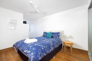 a bedroom with a bed with blue sheets and a table at 506 The Shoal in Shoal Bay