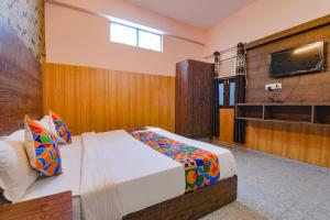 1 dormitorio con 1 cama y TV en la pared en FabHotel GSV Inn, en Kānpur