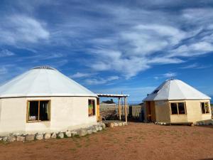 dos edificios yurta sentados en un campo con un cielo en Yurt camp Sonun en Bokonbayevo