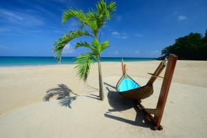 a hammock and a palm tree on a beach at Andaman White Beach Resort - SHA Plus in Nai Thon Beach