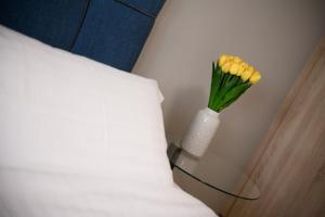 a vase with yellow flowers on a table next to a bed at Louloudis Apartment in Limenas