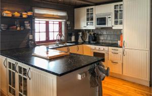 a kitchen with white cabinets and a black counter top at Cozy Home In seral With House A Mountain View in Åseral