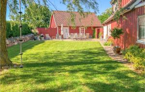 a yard next to a red house with a lawn at Stunning Home In Ystad With Sauna, 3 Bedrooms And Wifi in Ystad