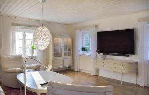 a living room with a flat screen tv and a table at Stunning Home In Ystad With Sauna, 3 Bedrooms And Wifi in Ystad