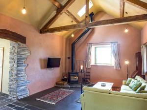 a living room with a couch and a stone fireplace at Tyn Llwyn Cornel Eco Barn in Penrhyndeudreath