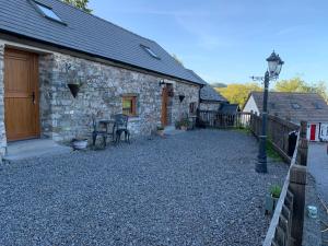 a stone house with a gravel yard next to a building at The Reindeer Retreat Buttercup Twin in Kidwelly