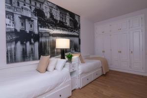2 letti in una camera bianca con una foto sul muro di Bilbao Henao Park de Bilbao Suites, en pleno centro con garaje directo a Bilbao