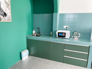 - une cuisine bleue avec évier et four micro-ondes dans l'établissement Garden Home Ipoh, à Ipoh