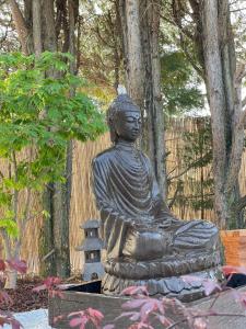 a statue of aitating buddha in a garden at Le GENKI japonais 4 étoiles in Saint-Cyr-sur-le-Rhône