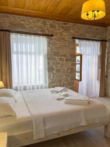 a bedroom with a large bed and two windows at Merlara Otel Alaçatı in Alaçatı