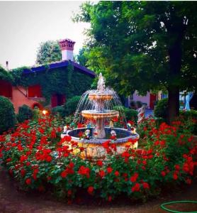 une fontaine au milieu d'un jardin avec des fleurs rouges dans l'établissement Cascina CORTEPRIMAVERA, B&B del Baliot, à Passirano